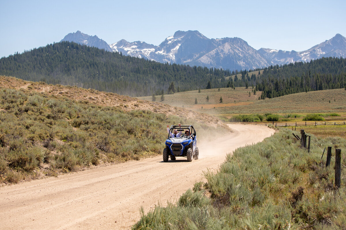 A bride and groom ride in a side-by-side towards their Idaho elopement photographer.