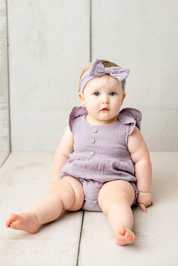Baby with chunky rolls poses her photos in studio.