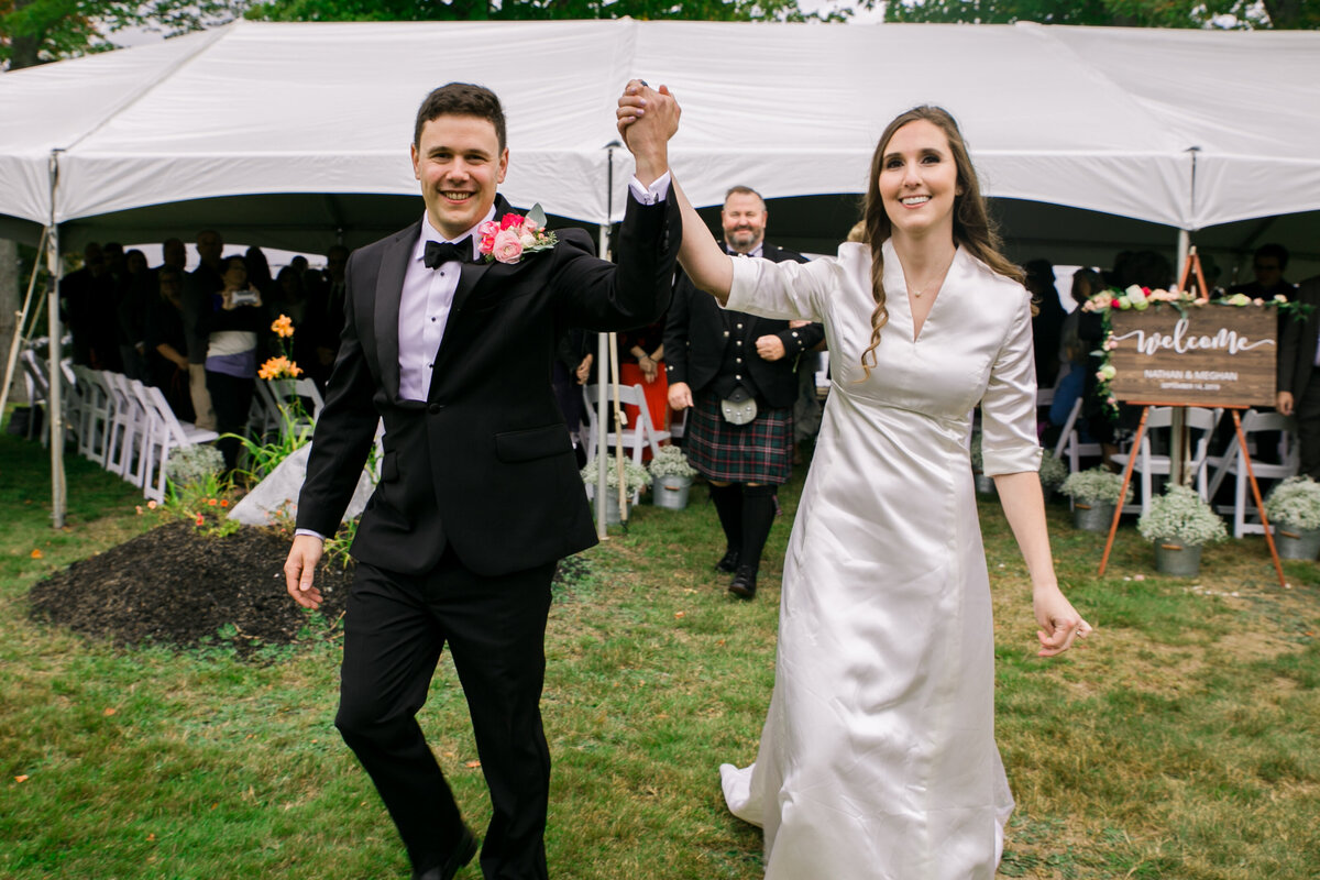 Couple exiting cermony holding hands with those hands in the air | Wedding Photography Taken by Maine Wedding Photographer