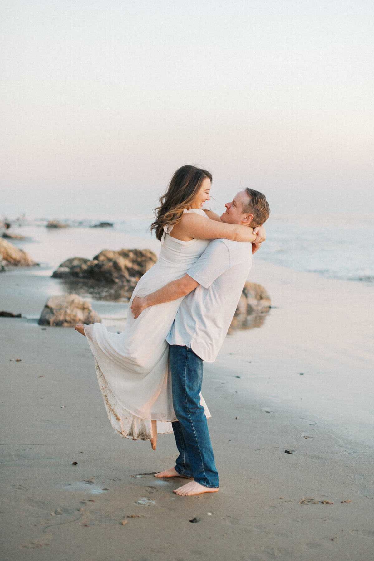 Capture the romance of Santa Barbara with this beach engagement photography at Hendry's Beach. Featuring a joyful couple embracing on the sandy shore during a stunning sunset. Perfect for engagement and wedding inspiration.