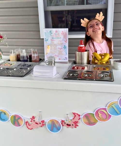 White snack cart with pink balloon setup at birthday party
