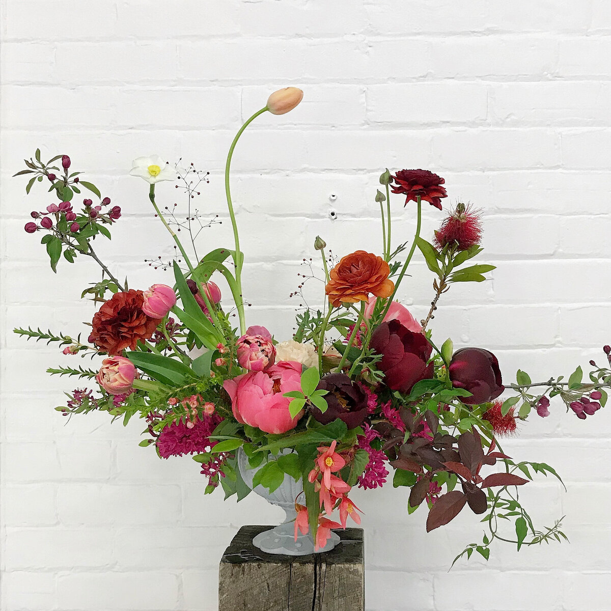 An airy arrangement of spring flowers and lush greenery sits on a stool at a Montreal wedding. 