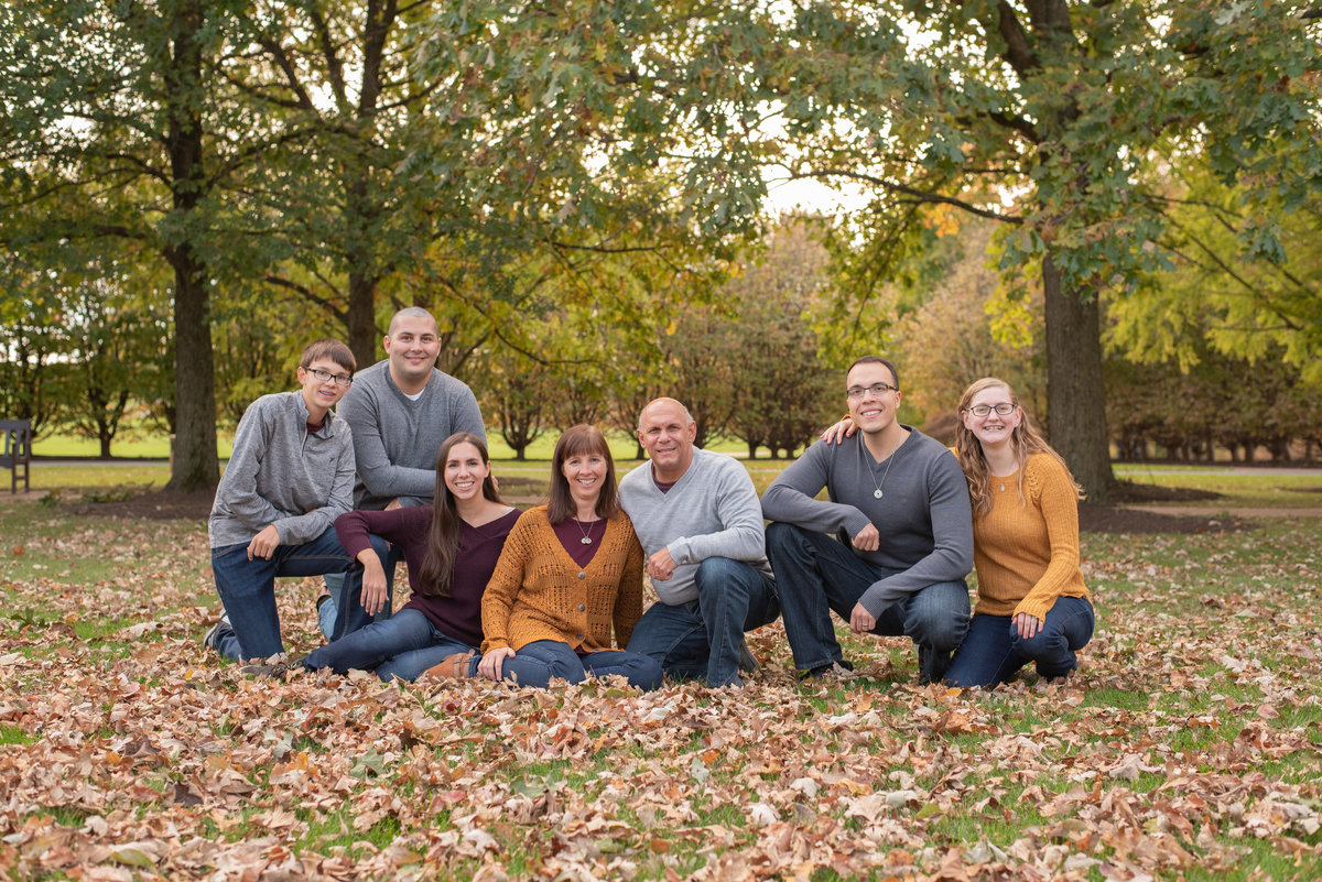 Extended family sitting on lawn covered with fallen leaves