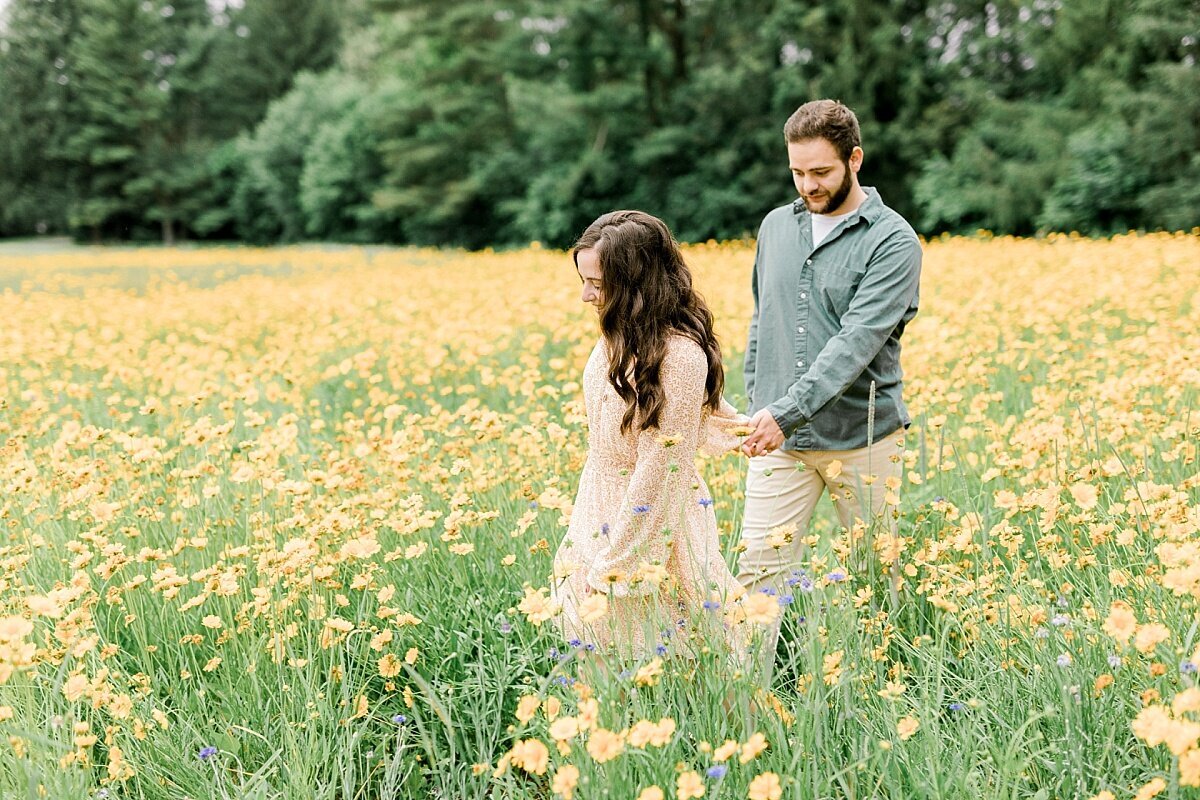 Couple walking through field of yellow flowers