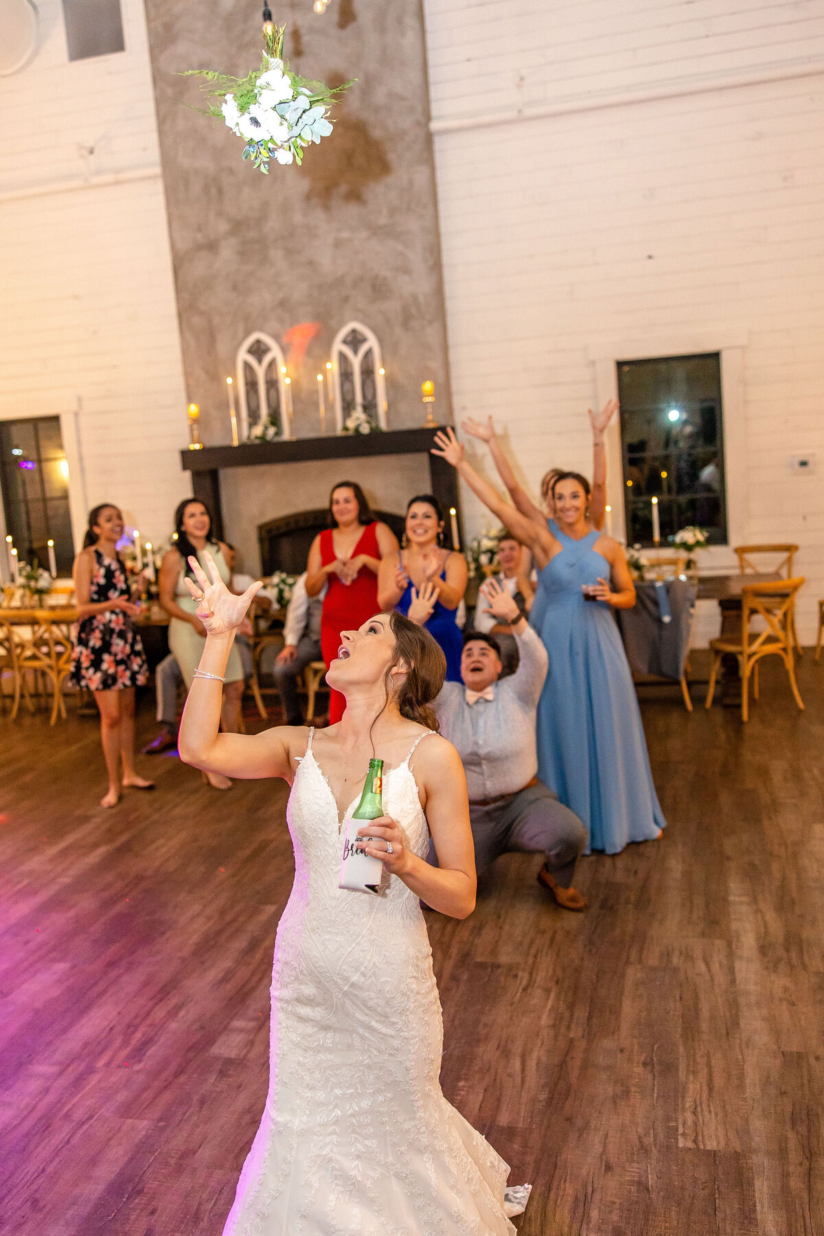 bride tosses bouquet while crowd reaches to catch it at Morgan Creek Barn in Dripping Springs