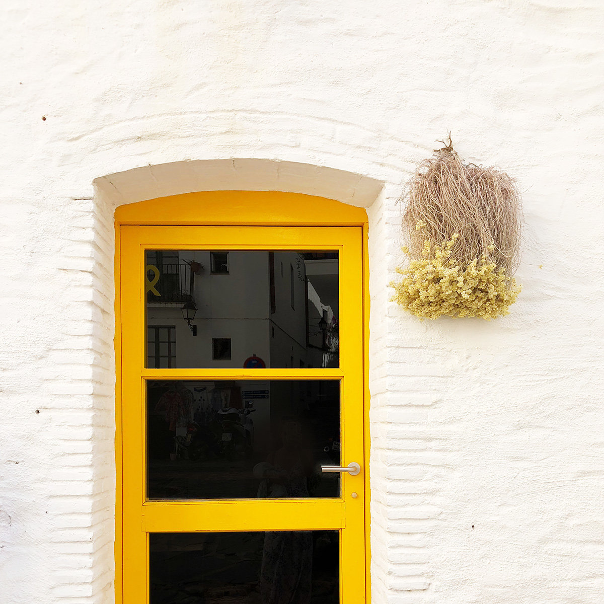 A large yellow door on a white brink building