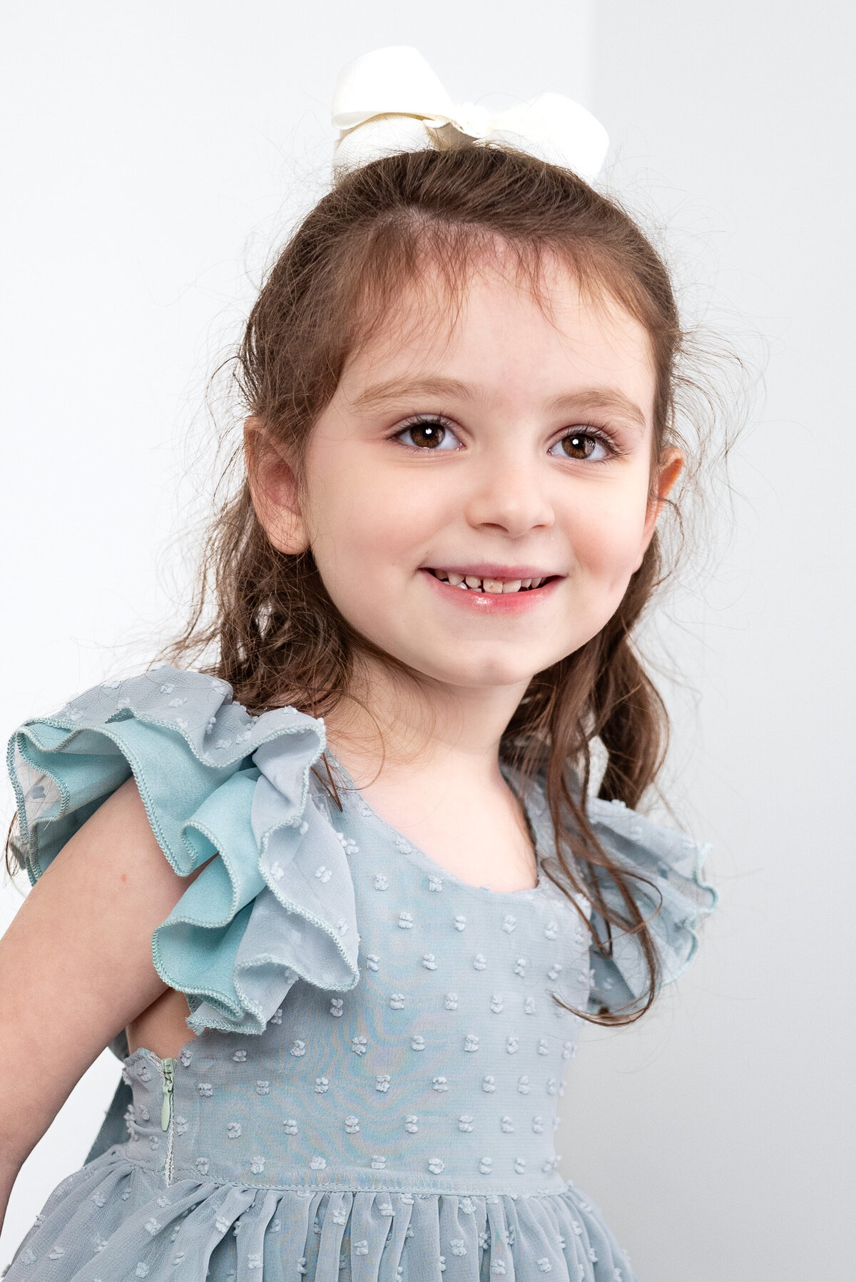 A young girl smiles at the camera  during family photos in a studio in Huntsville Alabama