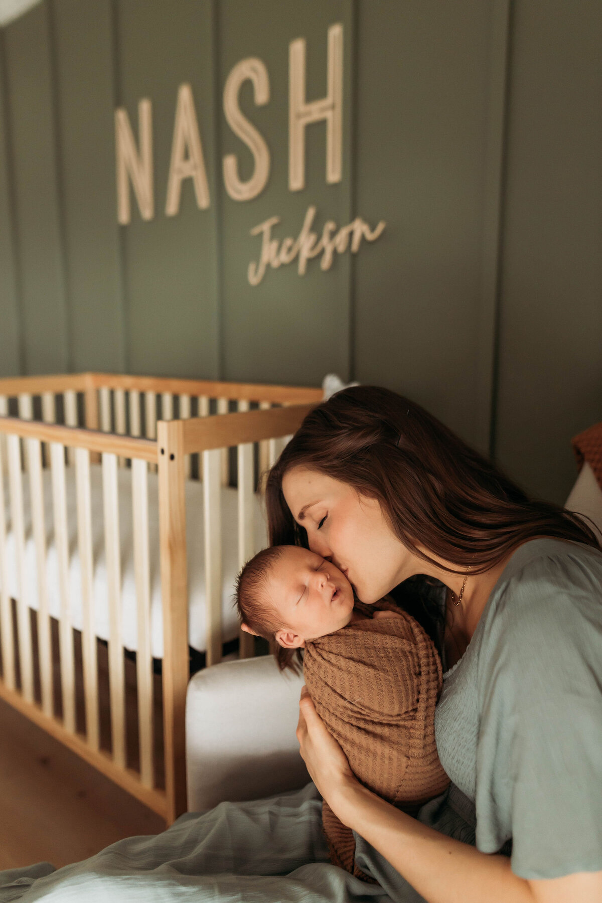 Mother kissing her baby in a rocking chair.