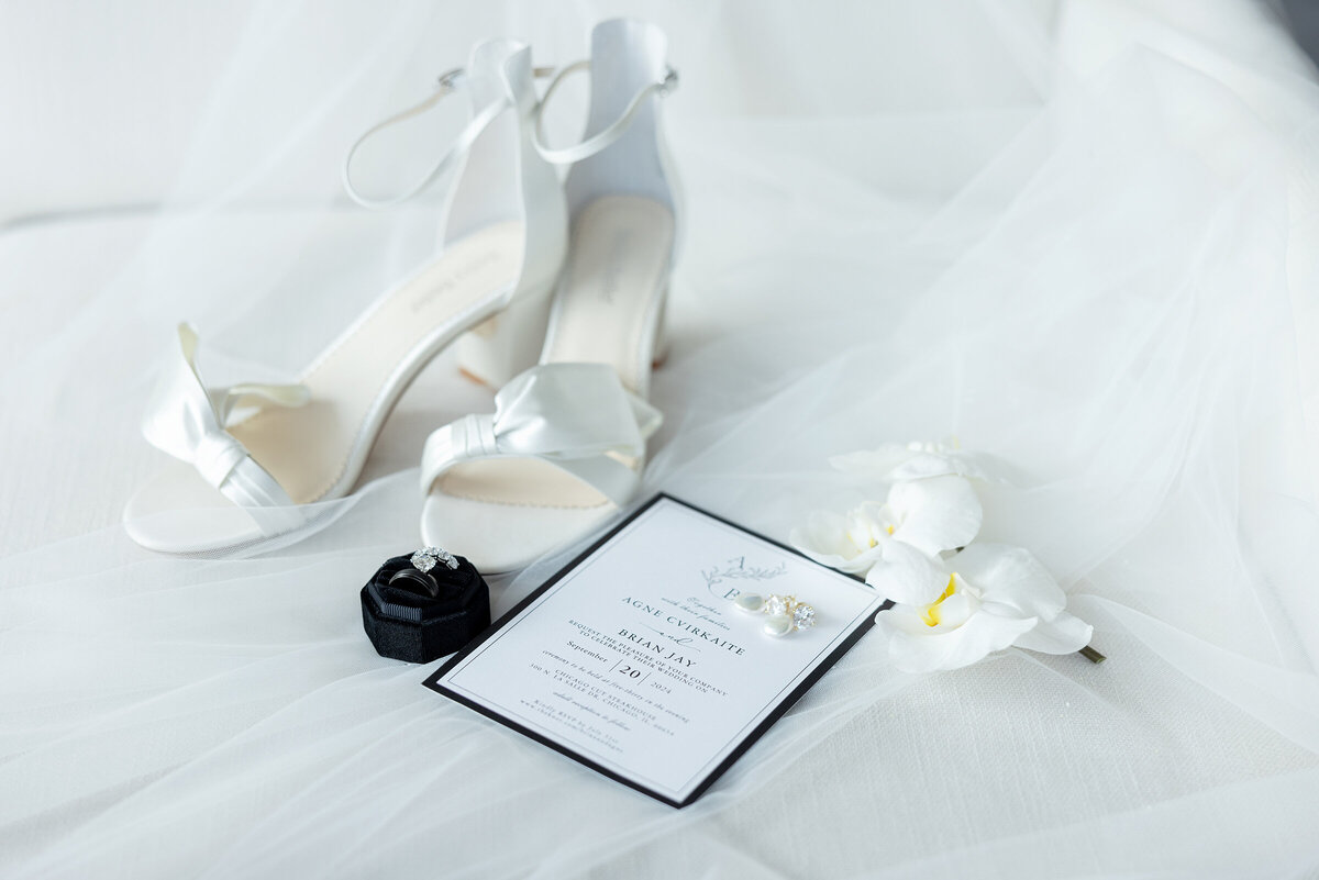 Bella belle bride shoes on top of the veil with rings, orchid and wedding invitation
