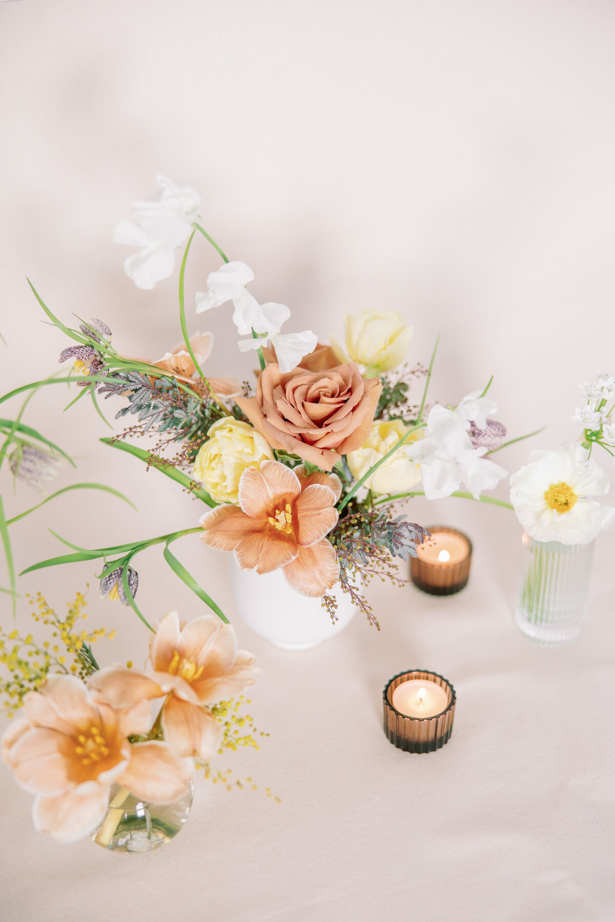 Bouquets are surrounded by candles against a white backdrop.