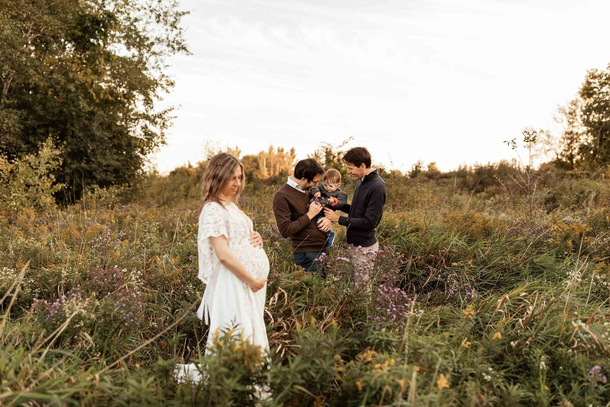 London Ontario maternity photography mom looking at belly with family in the distance