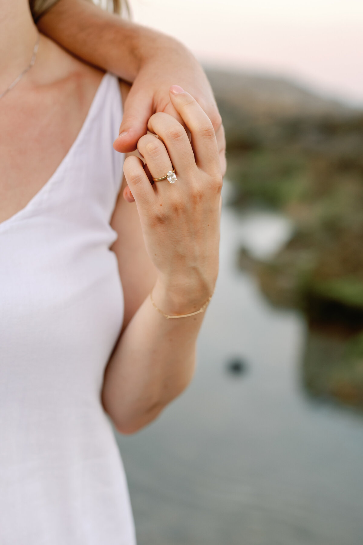 Close-up of engagement ring on couple's intertwined hands, Wilmington beach sand background