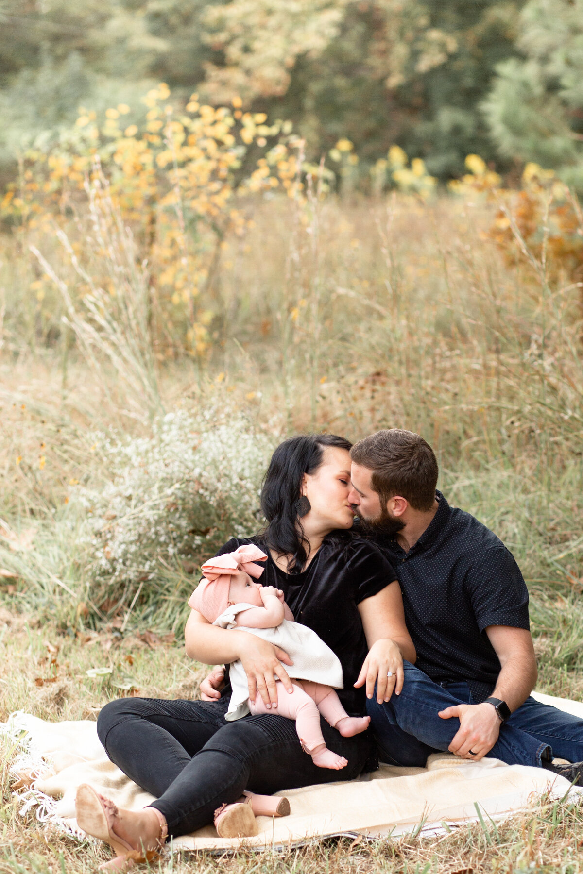a couple with a baby in a pink bow kiss