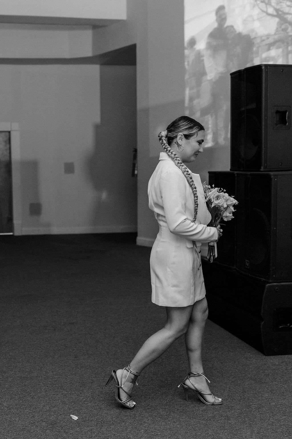 black and white photo of a bride walking along holding her bouquet