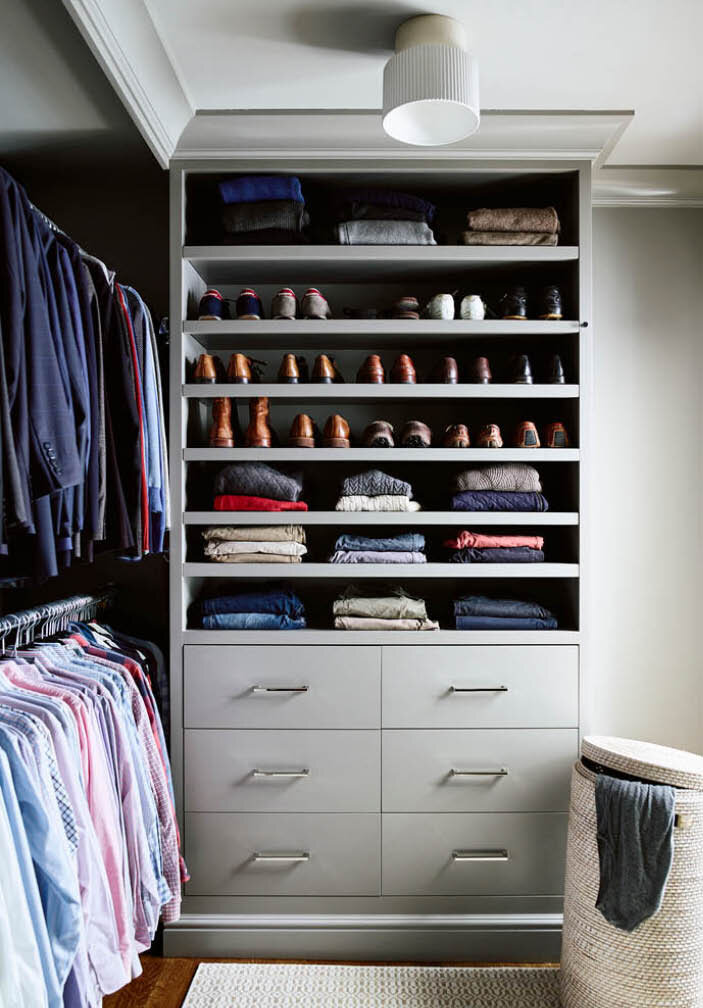 Custom grey cabinets tailored for his and her wardrobes with double hanging spaces, shelves for shoes and folded goods, and drawers. It all fits perfectly. By Sarah Scales.