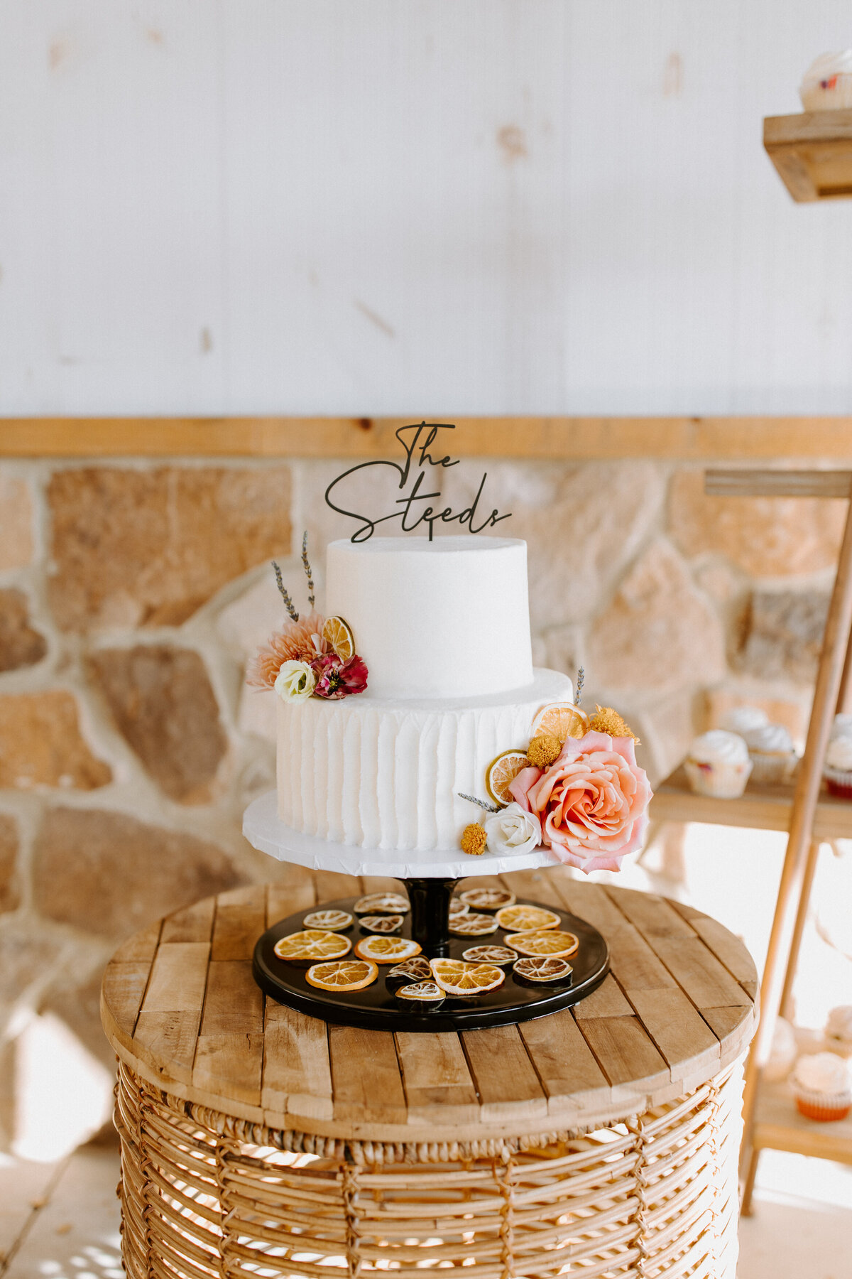 two-tiered wedding cake with flowers on it on a wood table