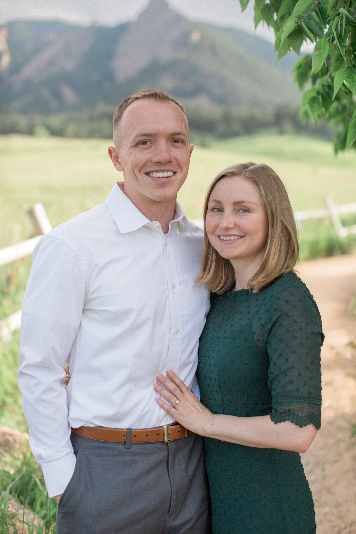 A woman poses with her left hand on her new fiance's chest, displaying her engagement ring