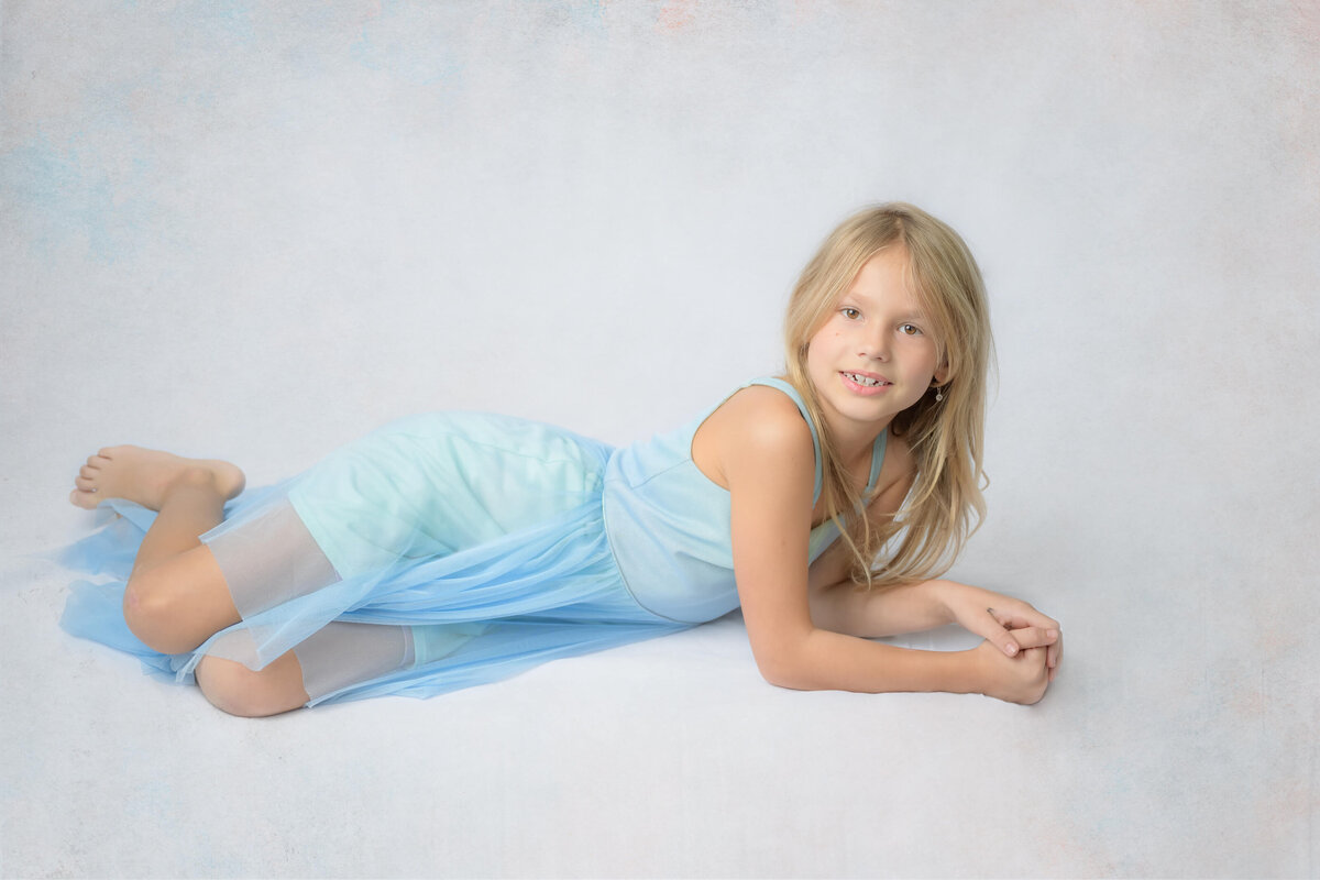 Young girl laying on a white background during a studio like in home family photo session captured by E. Benecki Photography.