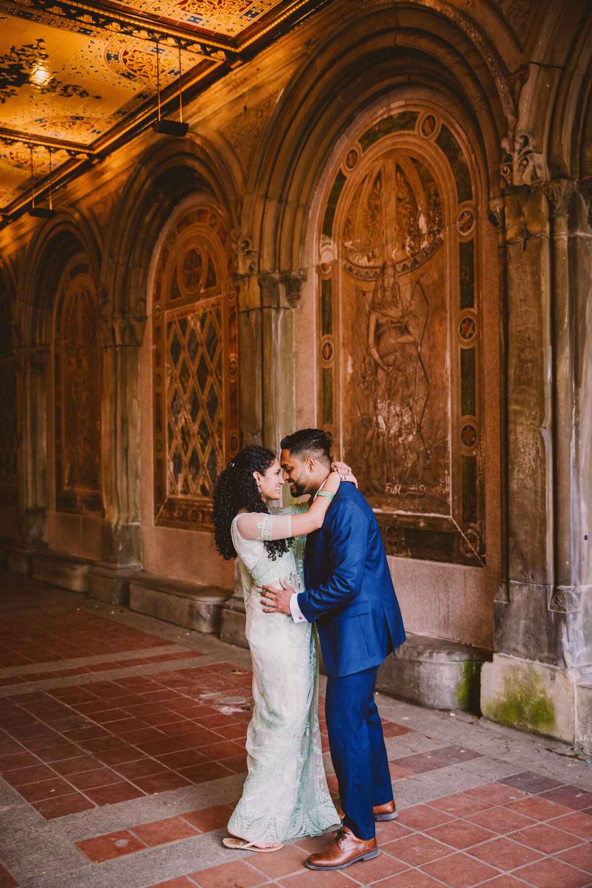 A couple wearing indian sari in front of the mural arches at bethesda terrace in central park in new york city