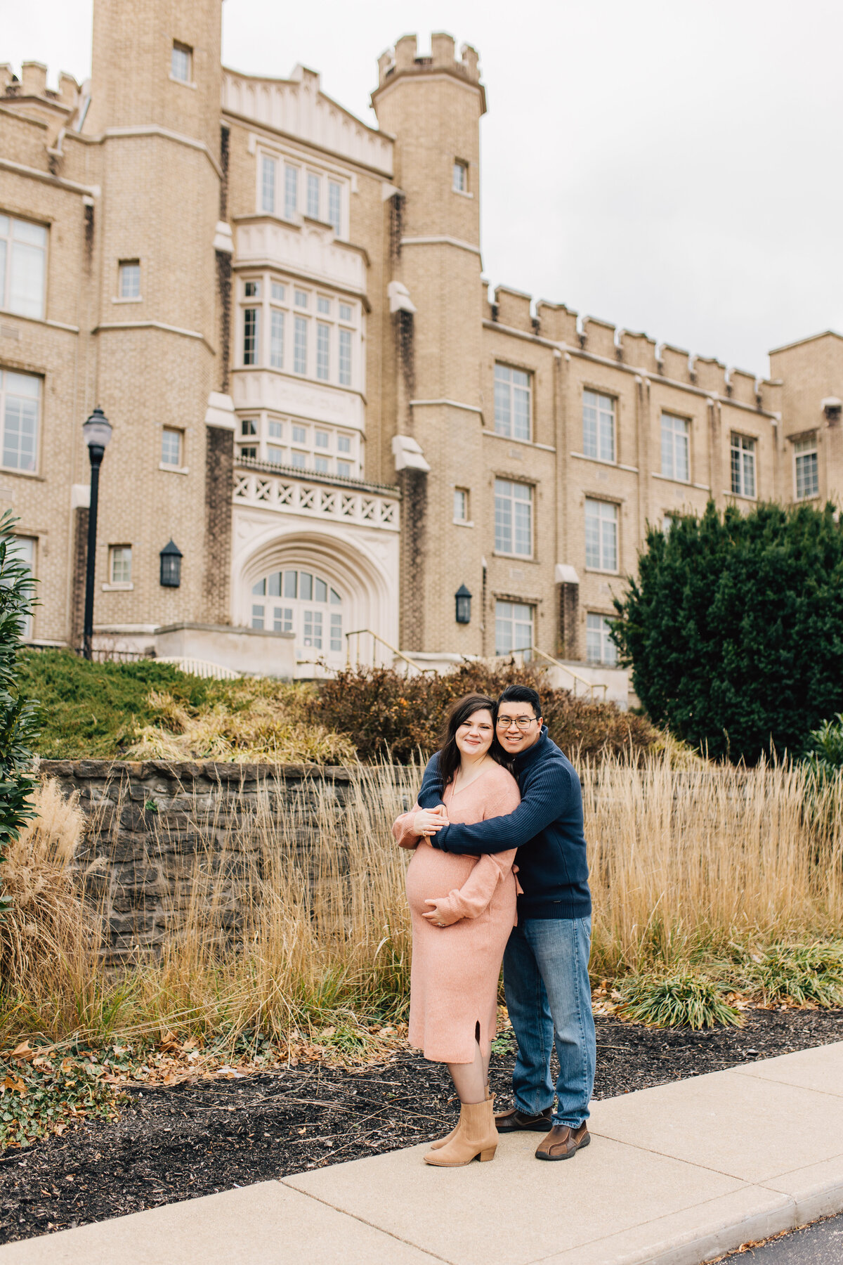 Husband and pregnant wife posing near buildings at Xavier University
