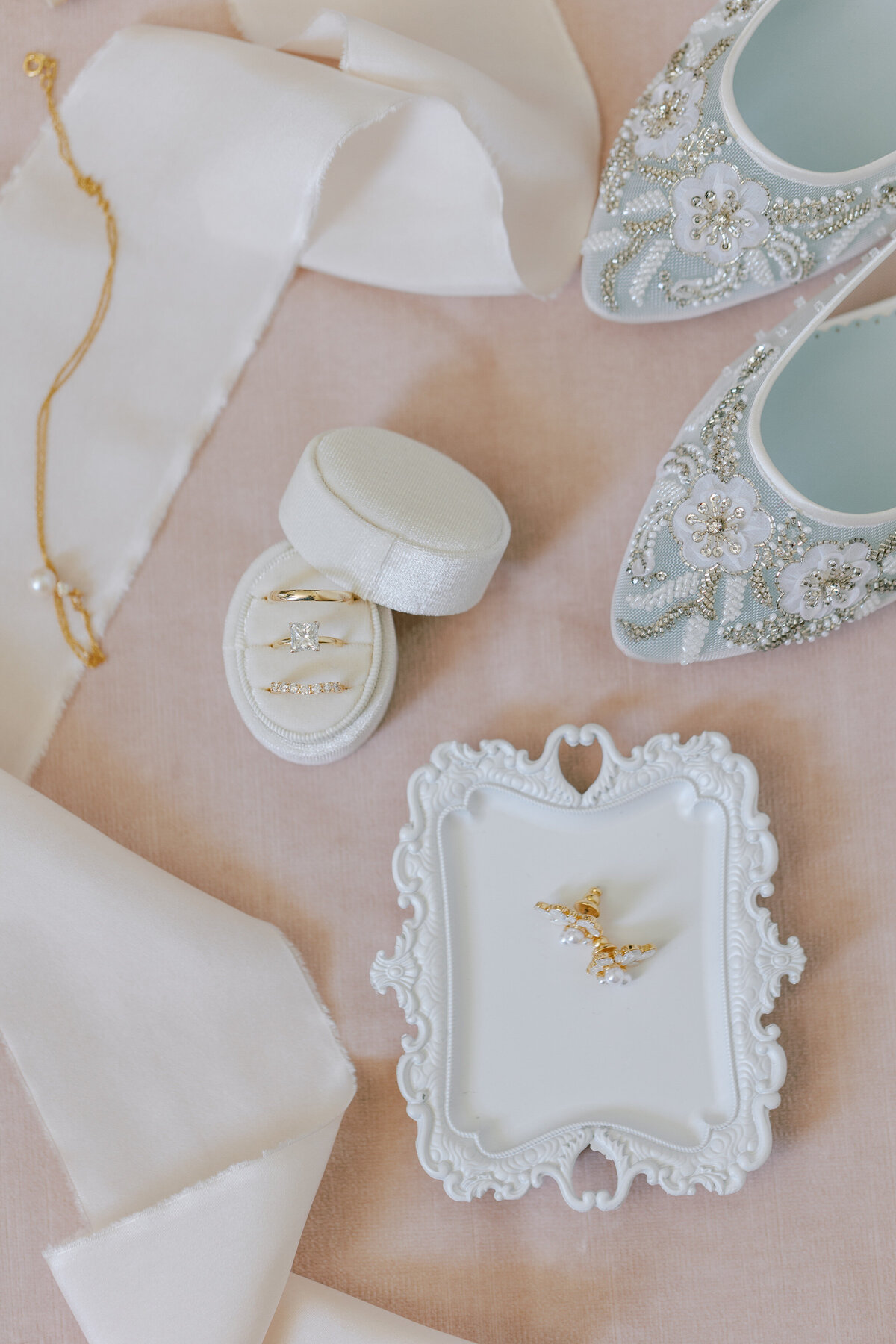 Flat-lay of white shoes and  diamond ring