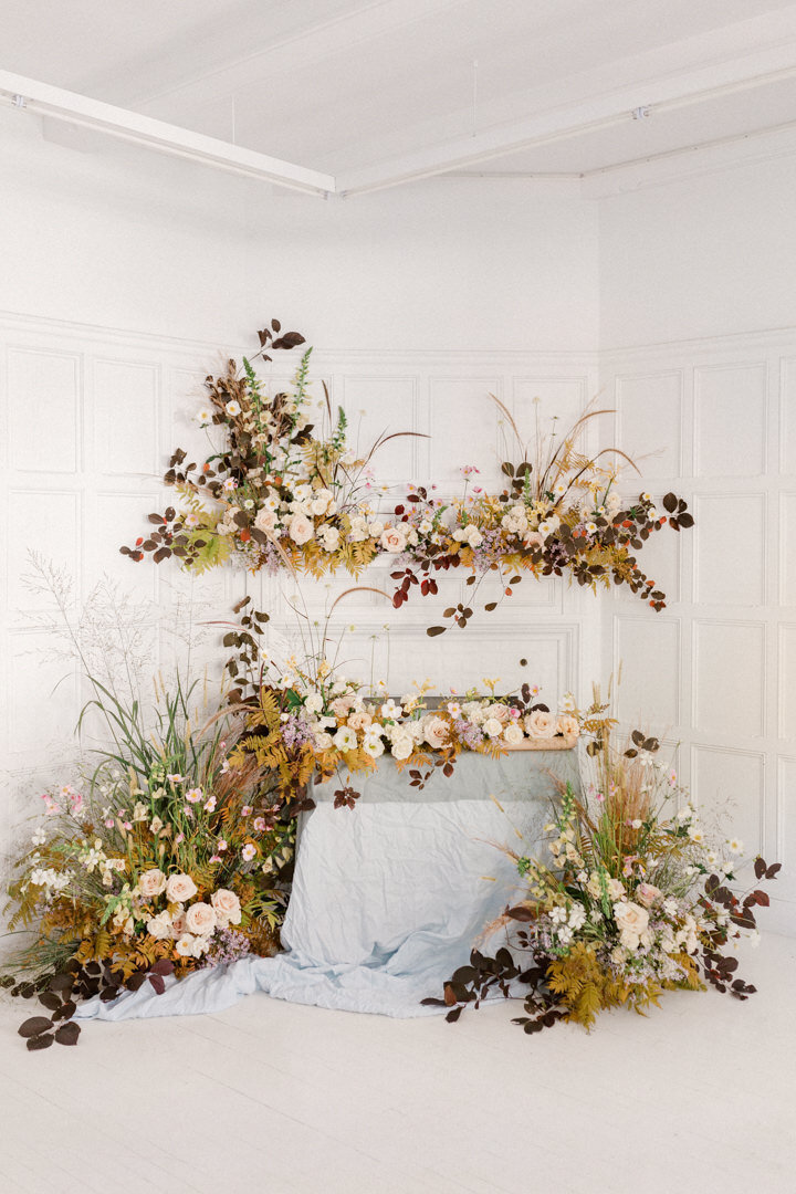 Large, organic, autumn flower arrangements surround the sweetheart table at a Livart wedding. 
