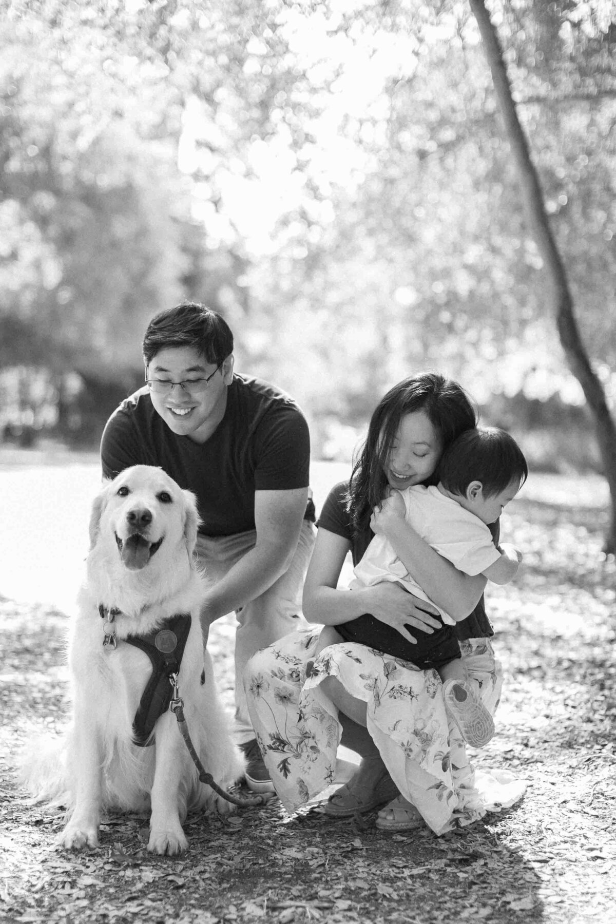 family of 3 hugging their golden retriever