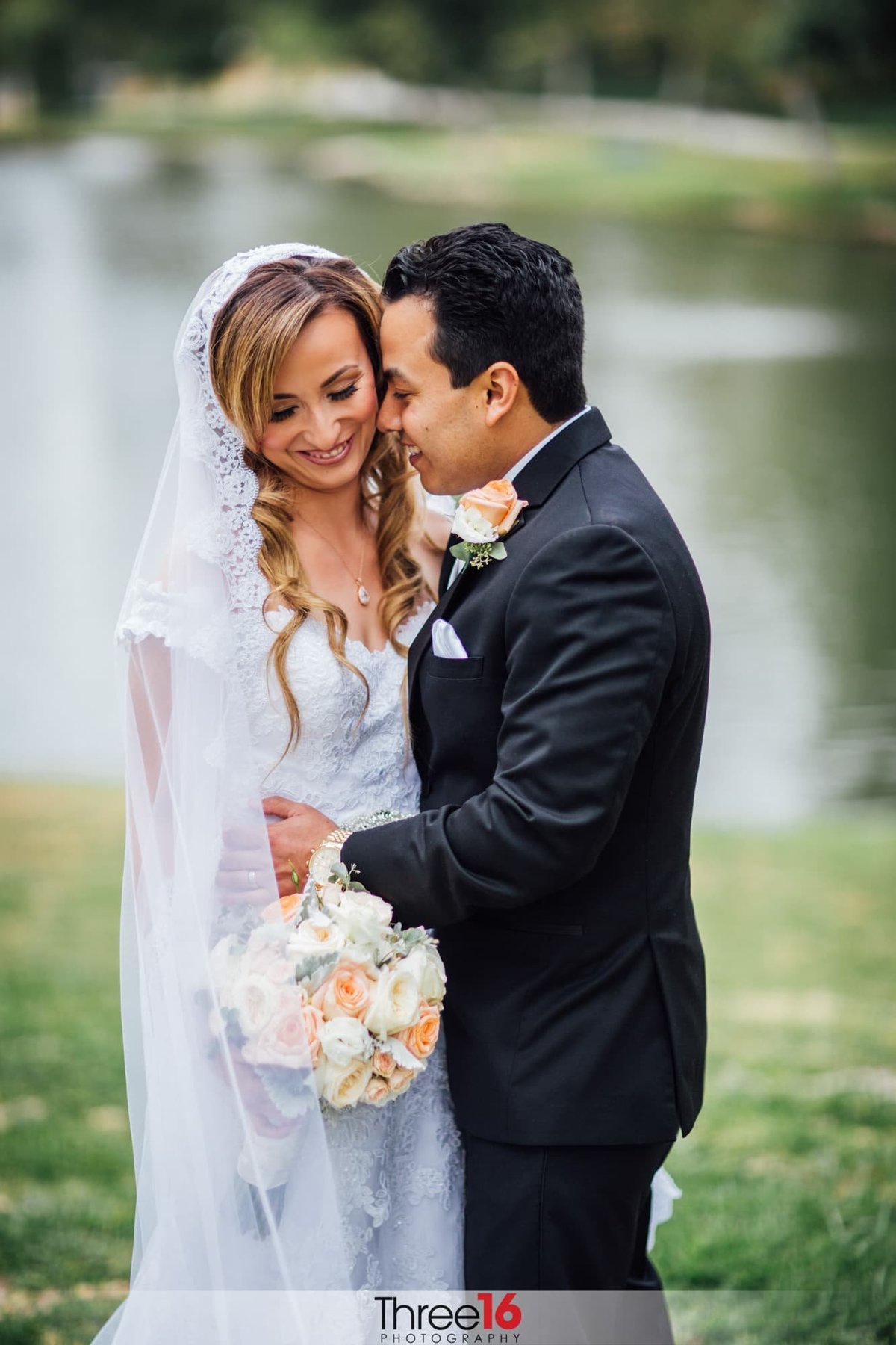 Tender moment between newly married couple with lake in the background