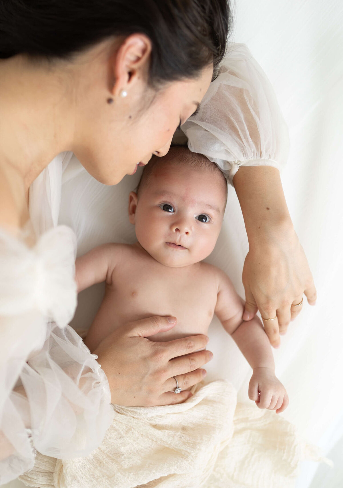 Mother on bed with newborn during intimate Bay Area newborn photography session.