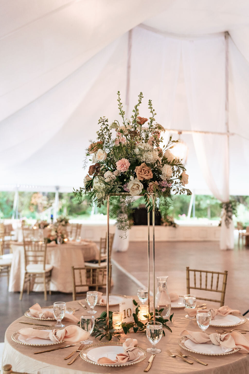Blush and neutral wedding flowers  on blush linens under a large tent  at Clarks Garden