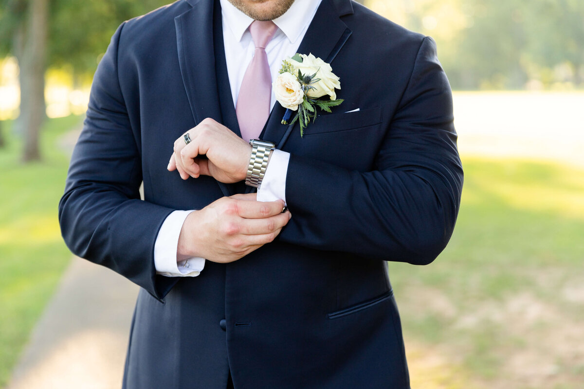 Groom adjusting cuffs of suit at Stones River Country club wedding