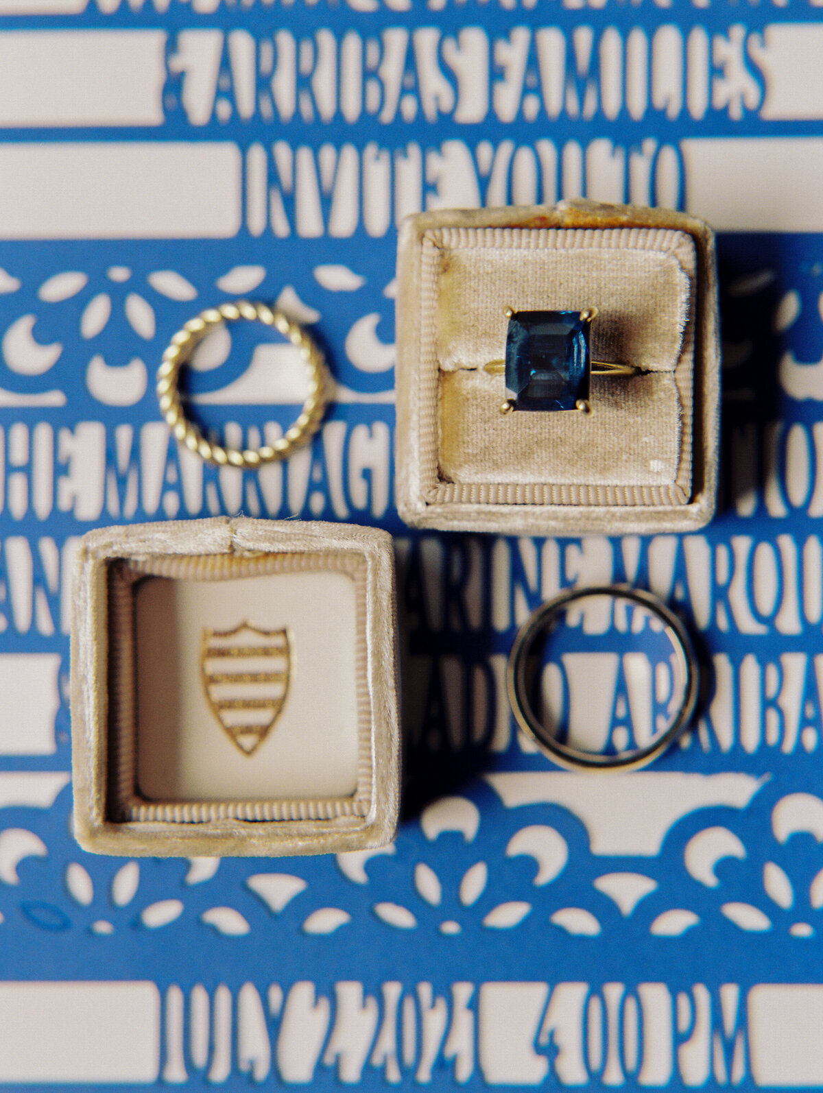 close up of blue engagement band in square cut inside a ring box that is tan  with blue lazer cut invitation