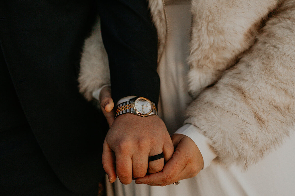 close up of bride and grooms hands and their jewelry