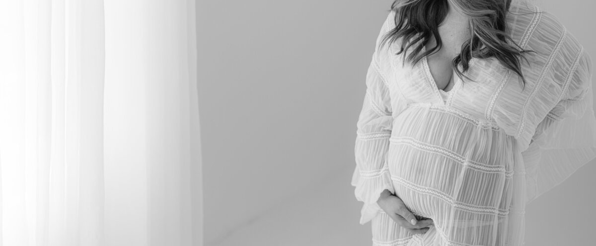 Pregnant woman in a flowing dress bathed in golden natural light, captured during an outdoor maternity session in Northern California by Suzanne Karp in Little Palm Studio.