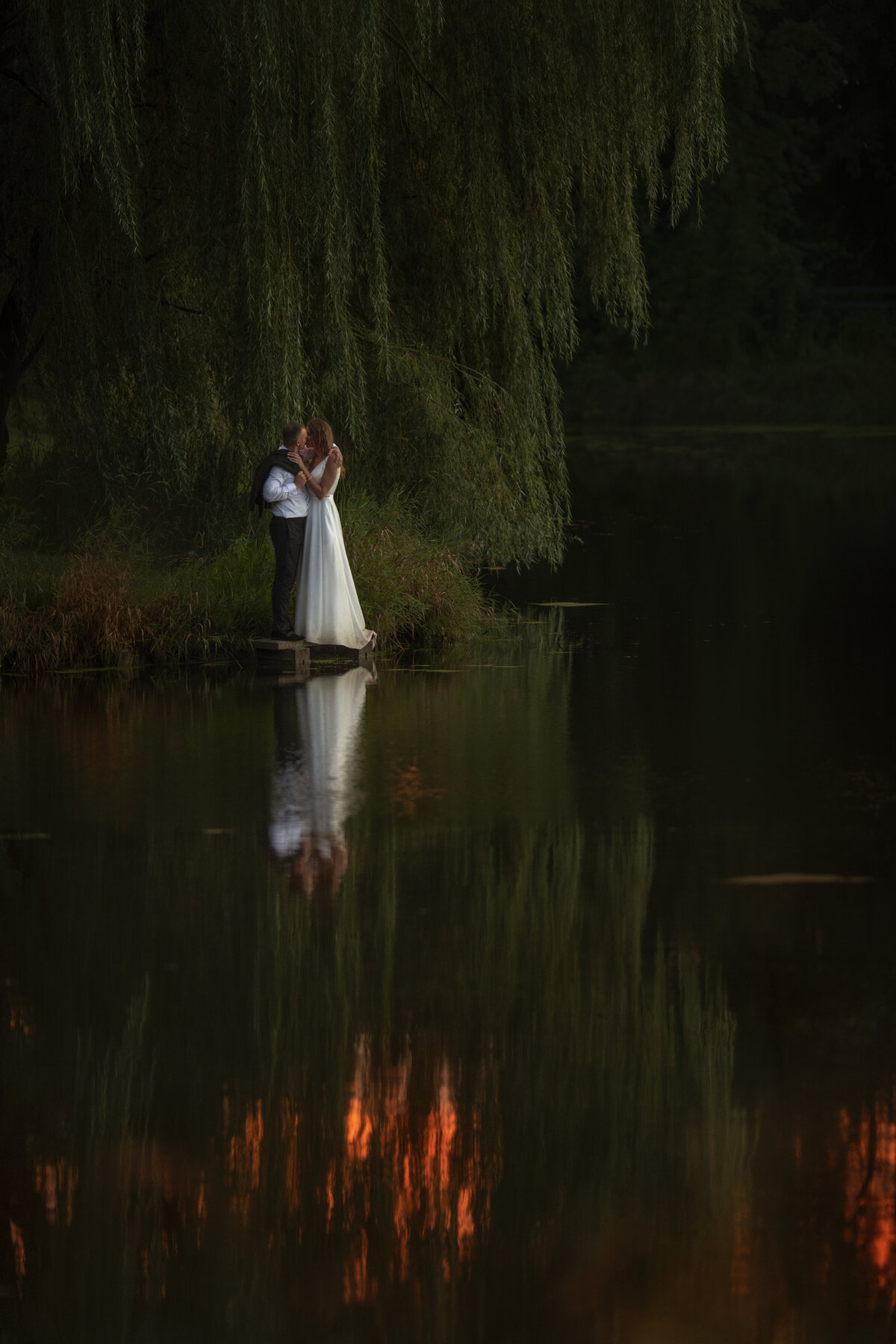 Bride and groom reflects on the lake during golden hour sunset photoshoot