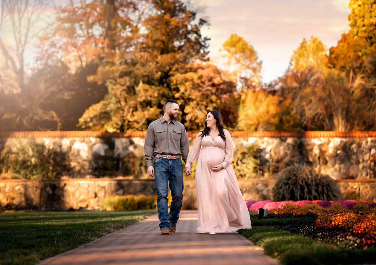 An adorable young couple expecting a baby walk down the garden paths at the Biltmore Estate in Asheville NC