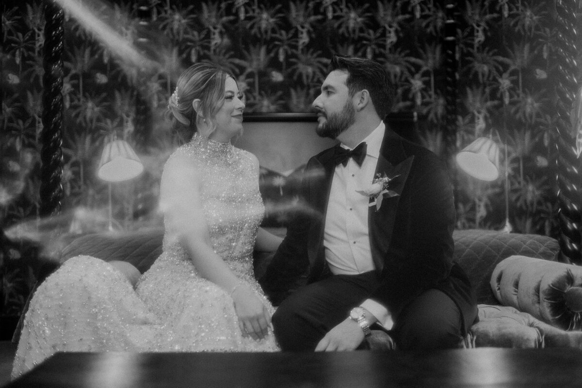 Bride and groom smiling at each other on bed