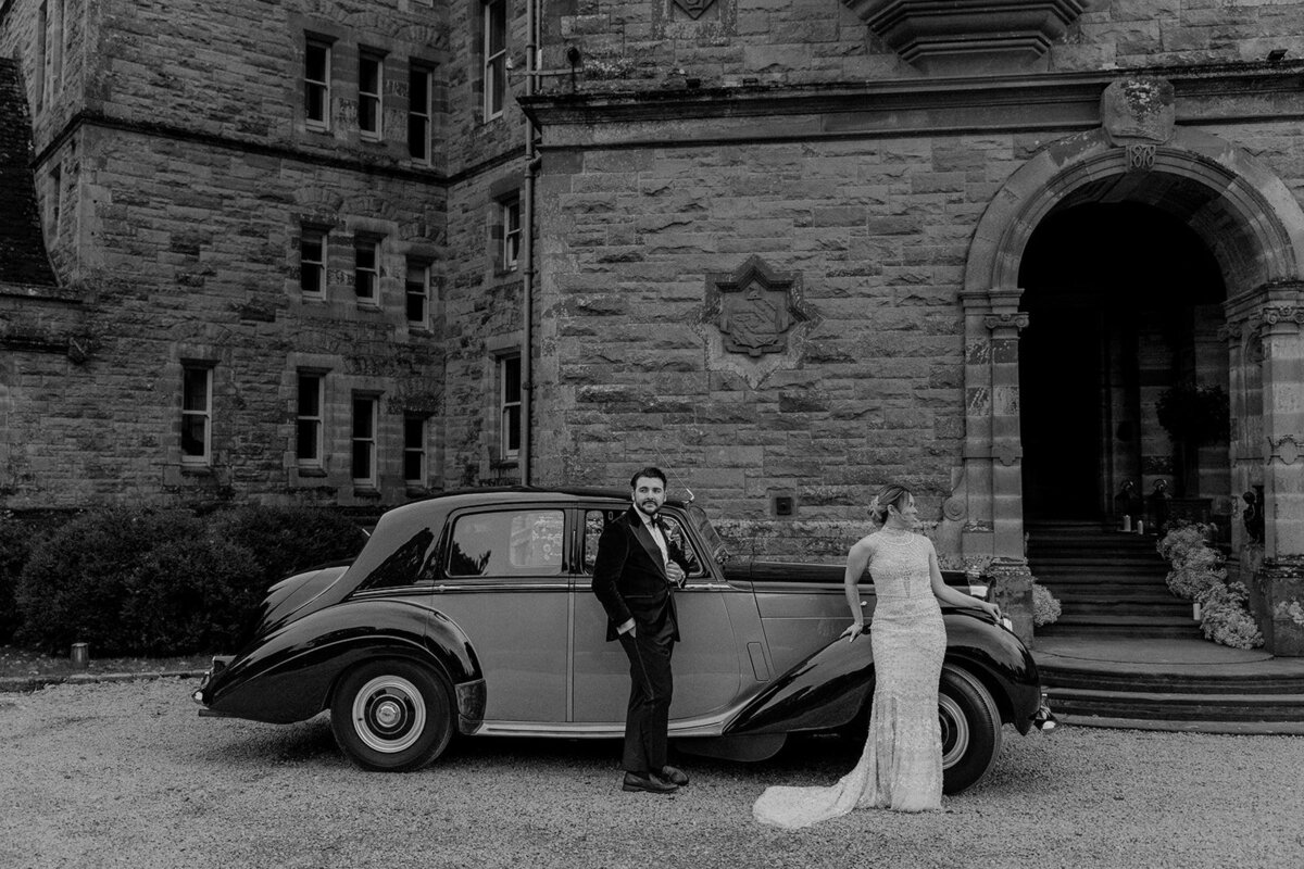 Bride and groom leaning against old car in Ireland