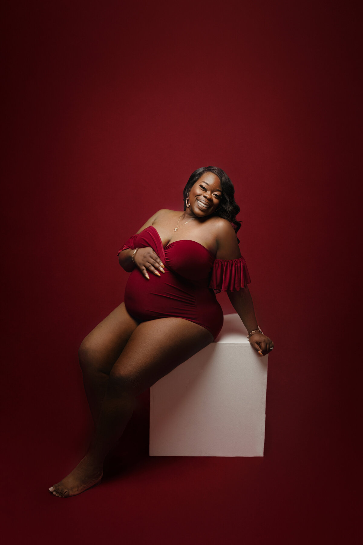 mom in red body suit for pregnancy photos in phoenix arizona maternity studio