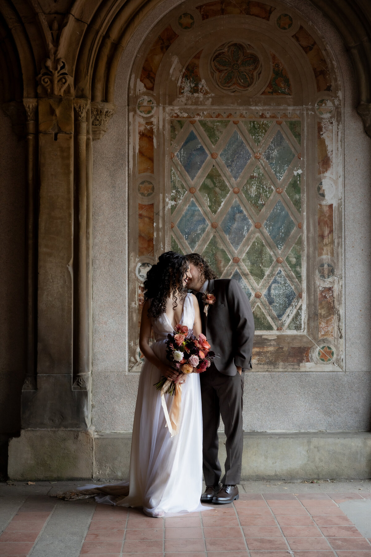 The couple sharing a tender moment beneath Central Park’s beautiful stone arches.