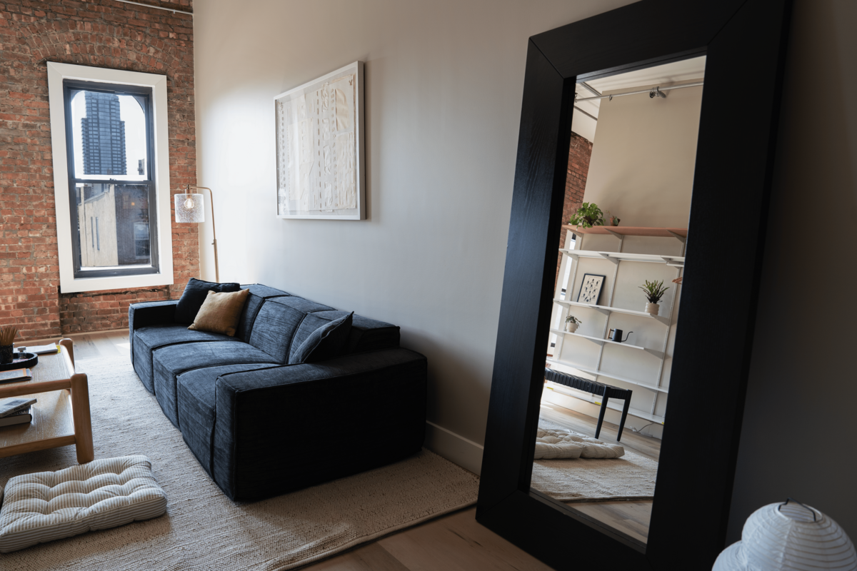 Welcome lounge with a large, cozy couch and a full-length mirror.
