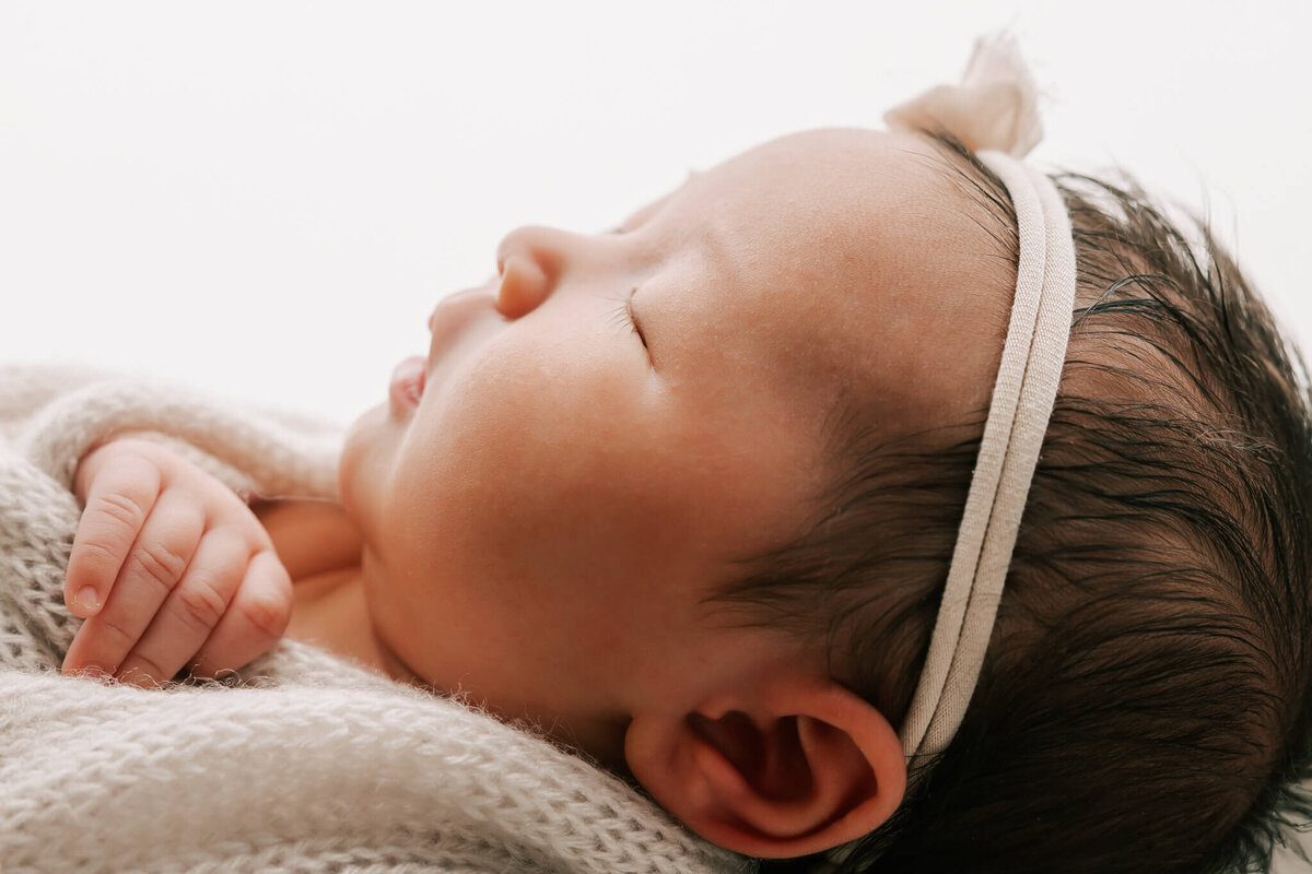 portrait of the side of a baby's face as she sleeps with a headband on