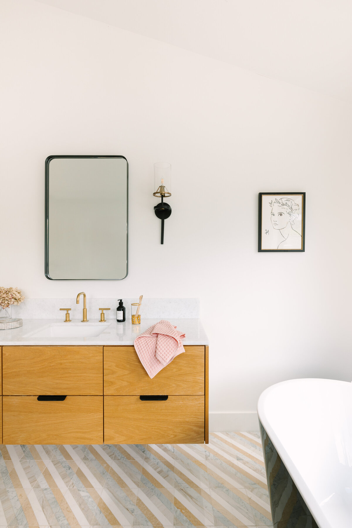Primary bathroom with floating vanity, chevron marble flooring and black freestanding tub