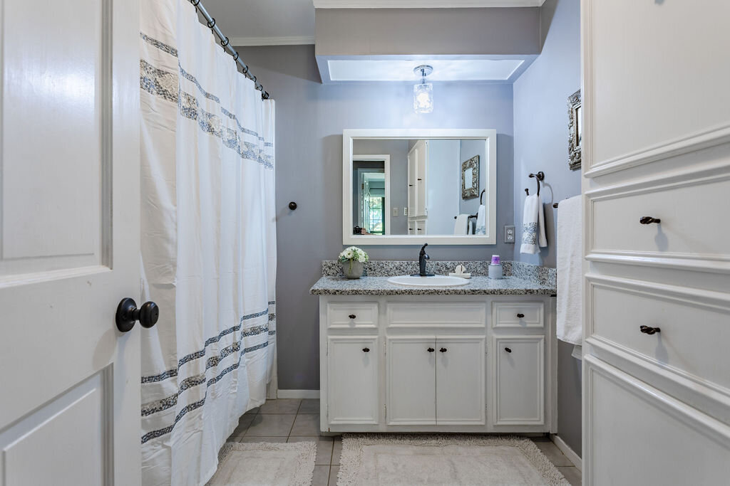 Bathroom with shower and plenty of cabinet space in this 5-bedroom, 4-bathroom vacation rental house for 16+ guests with pool, free wifi, guesthouse and game room just 20 minutes away from downtown Waco, TX.