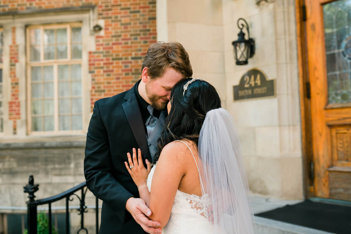 Bride and Groom snuggling close together for candid portraits by their reception venue in Hamilton, OH.