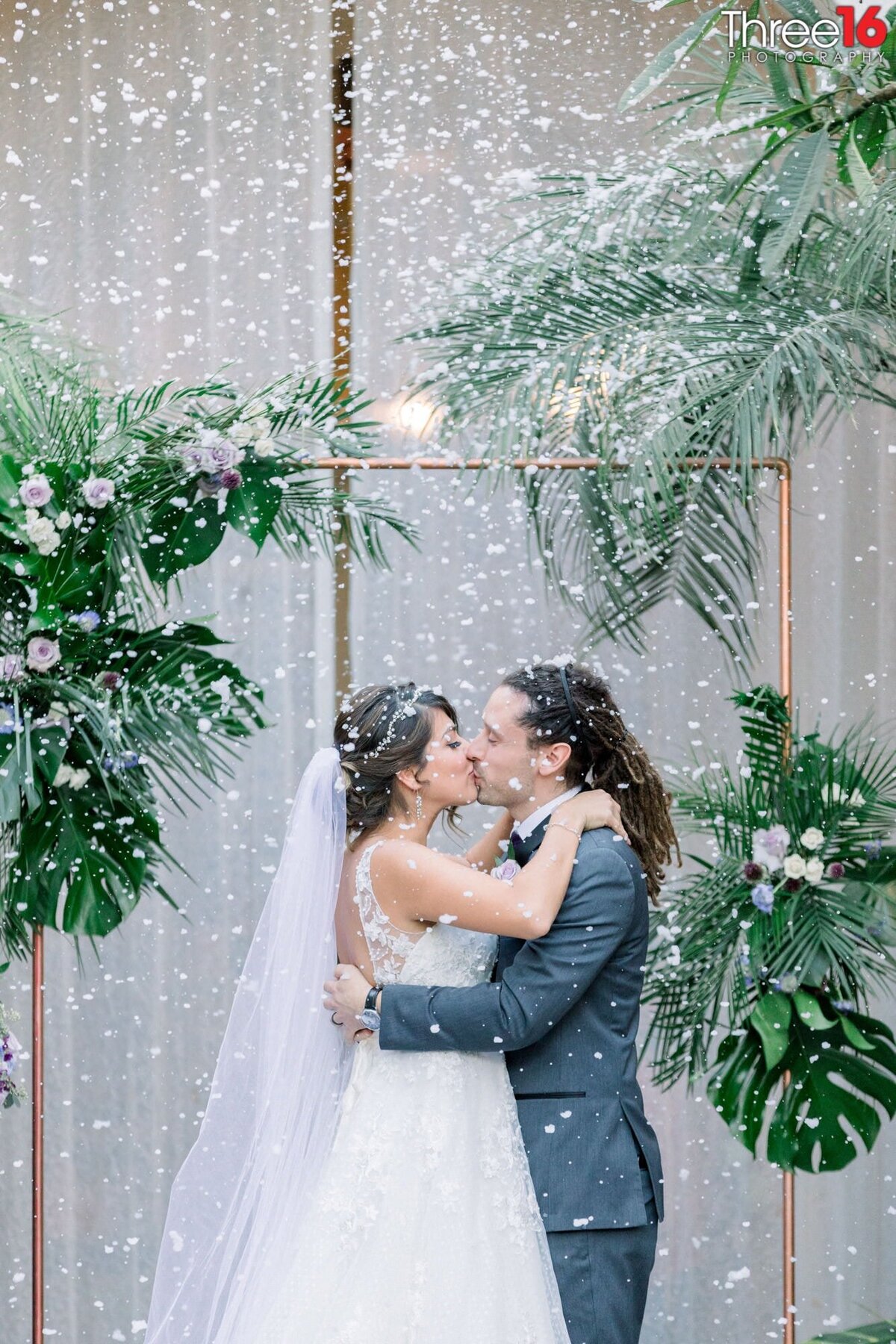 Bride and Groom share their first kiss as a married couple while confetti rains down on them