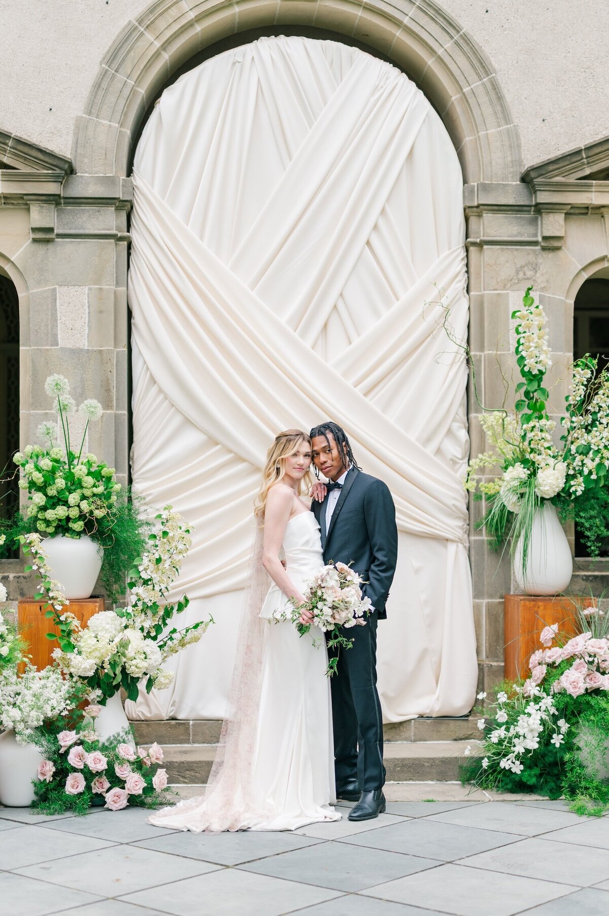 A bride and groom touching heads together in front of drapery at Glen Manor House. 