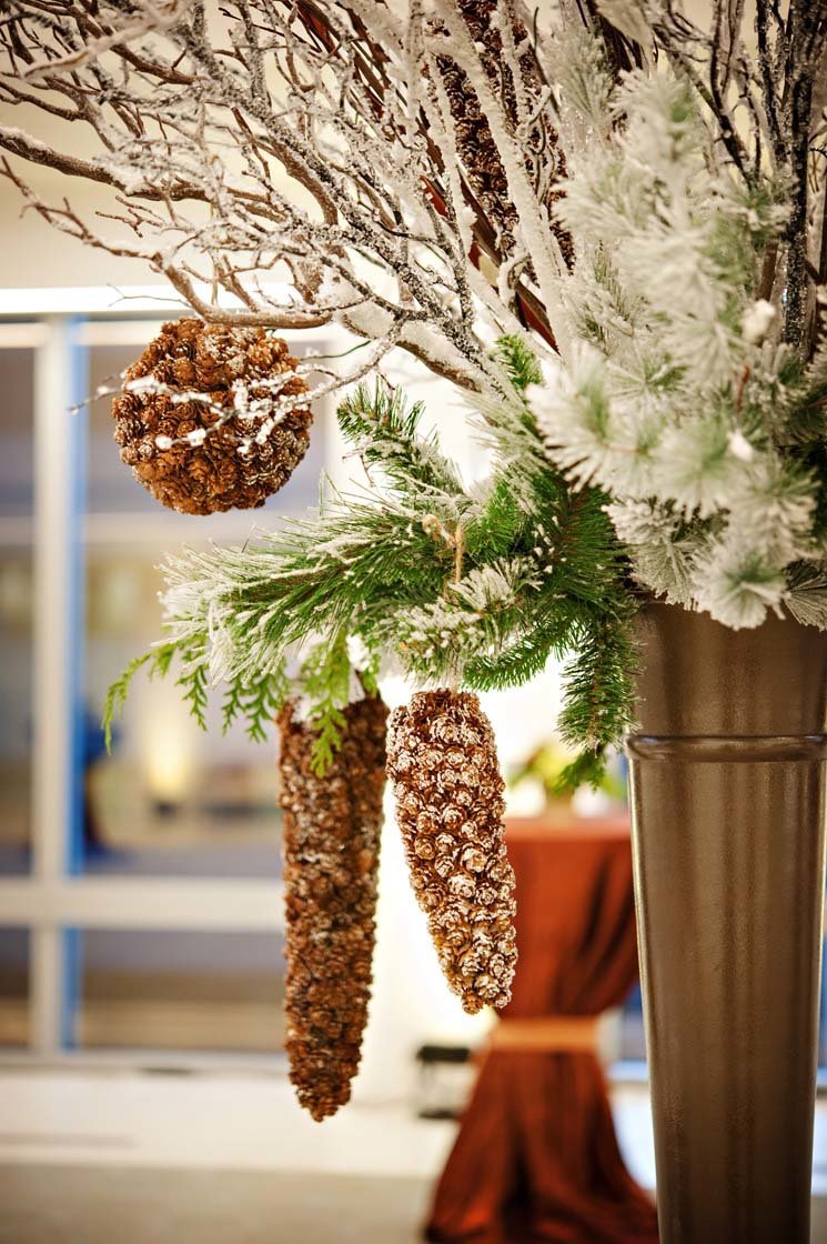 flocked acorn ornaments for holiday centerpiece in tall brown urn with evergreens and flocked branches