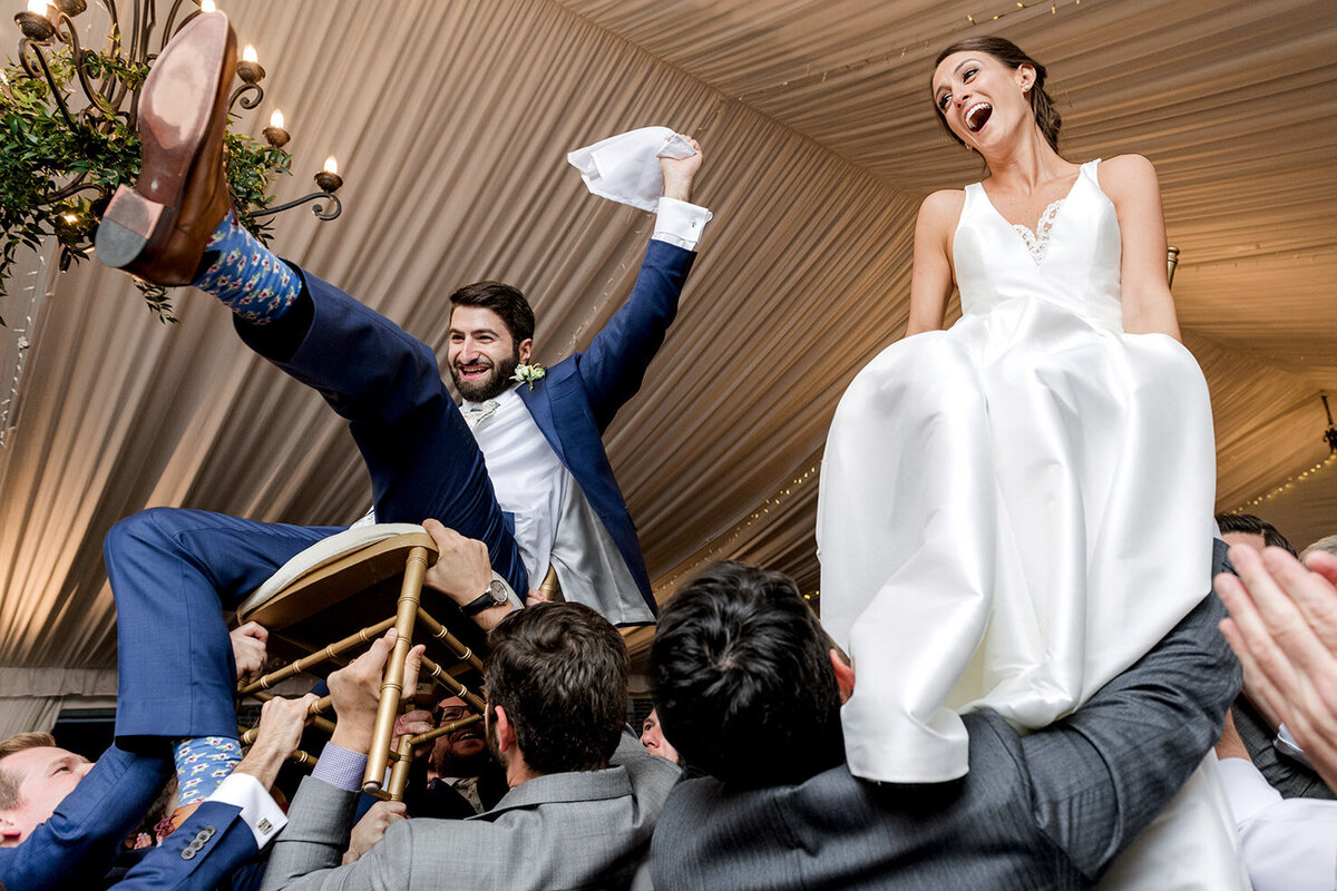 bride and groom up in chairs during the Hora