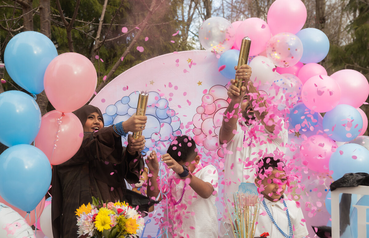 A joyful family moment as confetti pops, revealing pink confetti to announce the baby’s gender, surrounded by excited loved ones sharing in the happiness and anticipation of the new arrival.